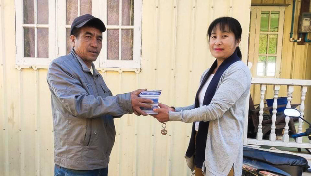 A person giving a stack of booklets to another.